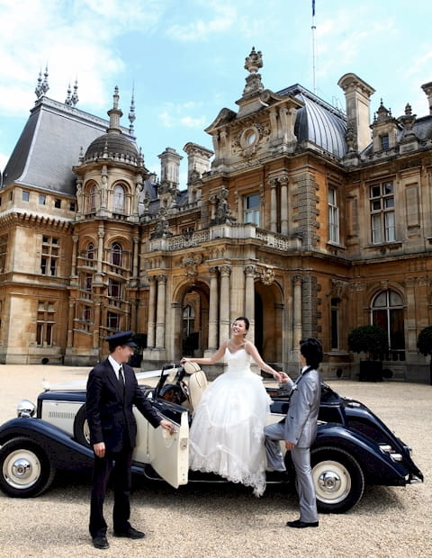 Jaguar Drophead with the Bride, Groom and chauffeur opening the door. Waddesdon manor features in the background